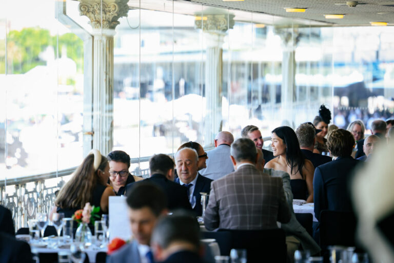 People seated at tables at a restaurant located within a racecourse grandstand
