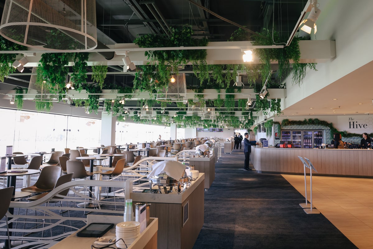 The indoor area of a restaurant at a racecourse, with lush greenery suspended from the ceiling