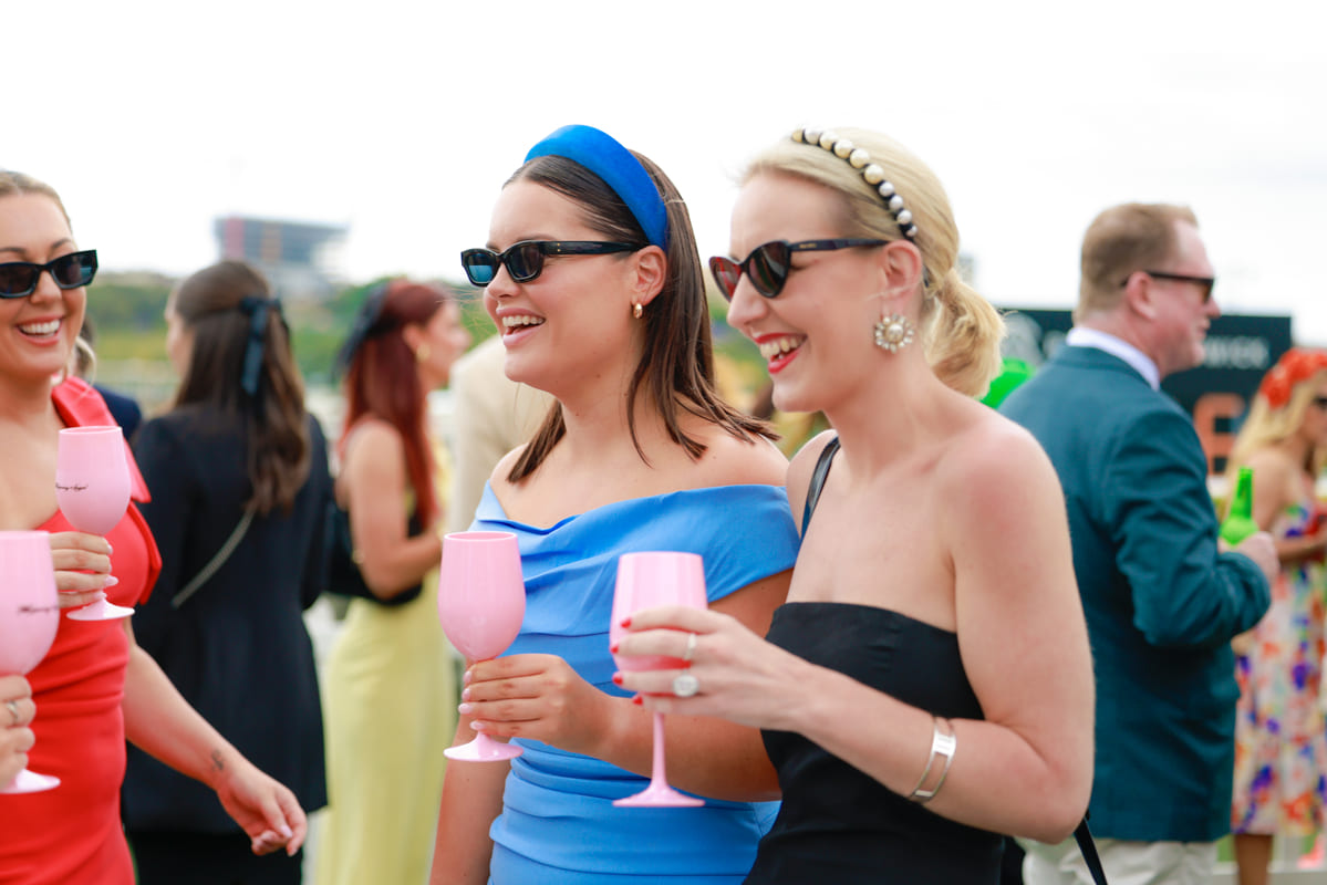A group of woman socialise while drinking wine at a racecourse