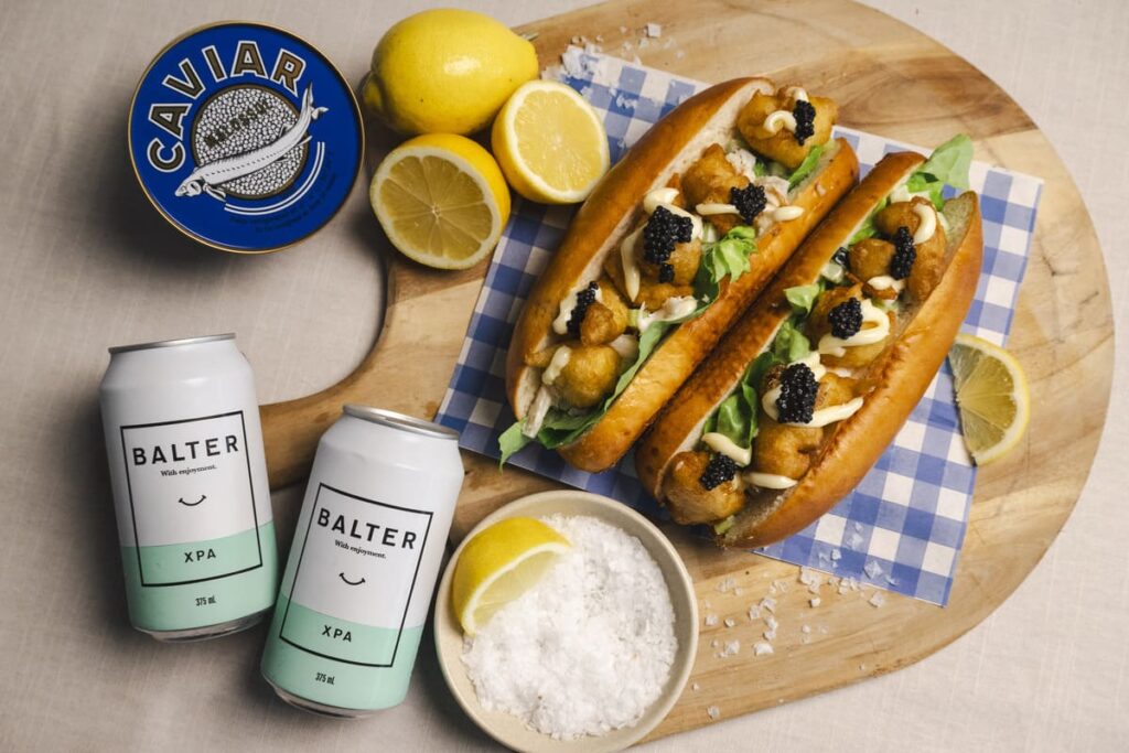 Lobsters rolls are displayed with beer, lemons, salt and caviar.