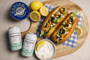 Lobsters rolls are displayed with beer, lemons, salt and caviar.