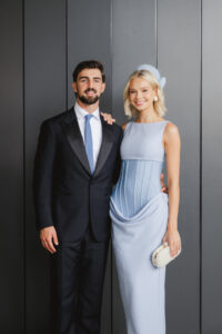 An influencer couple dressed for the races poses for a photo.