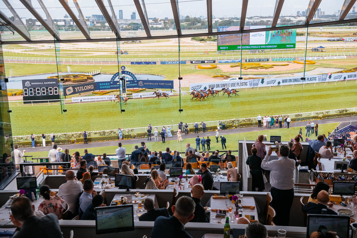 Racegoers watch horses from within a grandstand restaurant at Rosehill Gardens.