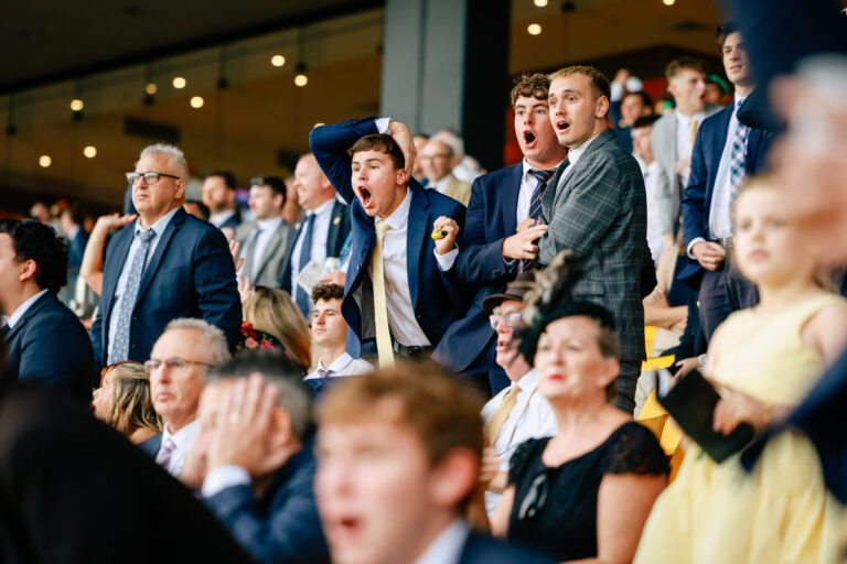 A group of young men excitedly watch a race at Rosehill Gardens.