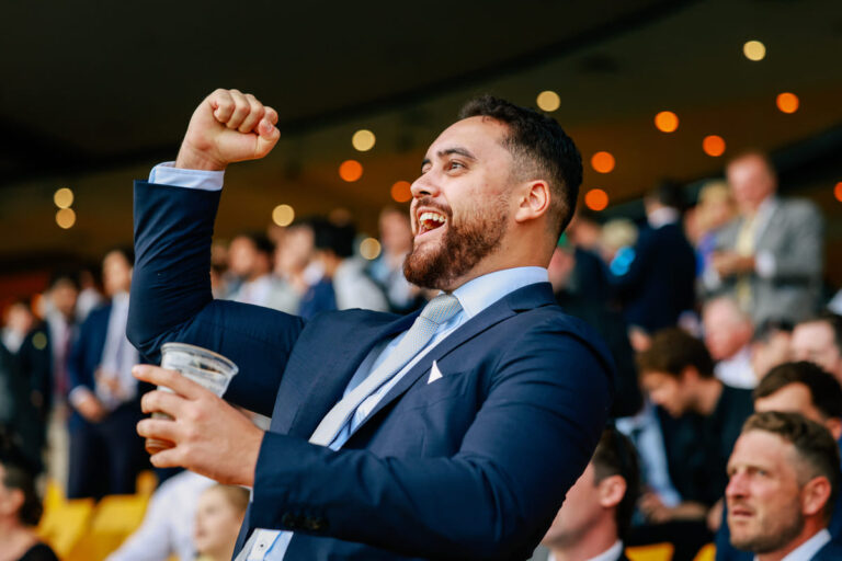 A male racegoer at Rosehill Gardens raises his fist in celebration.