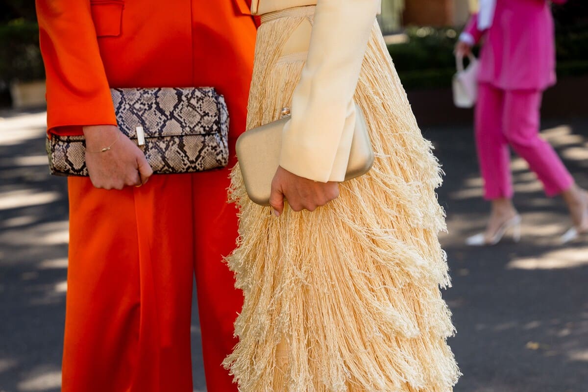 Close-up of female racegoers holding clutches.