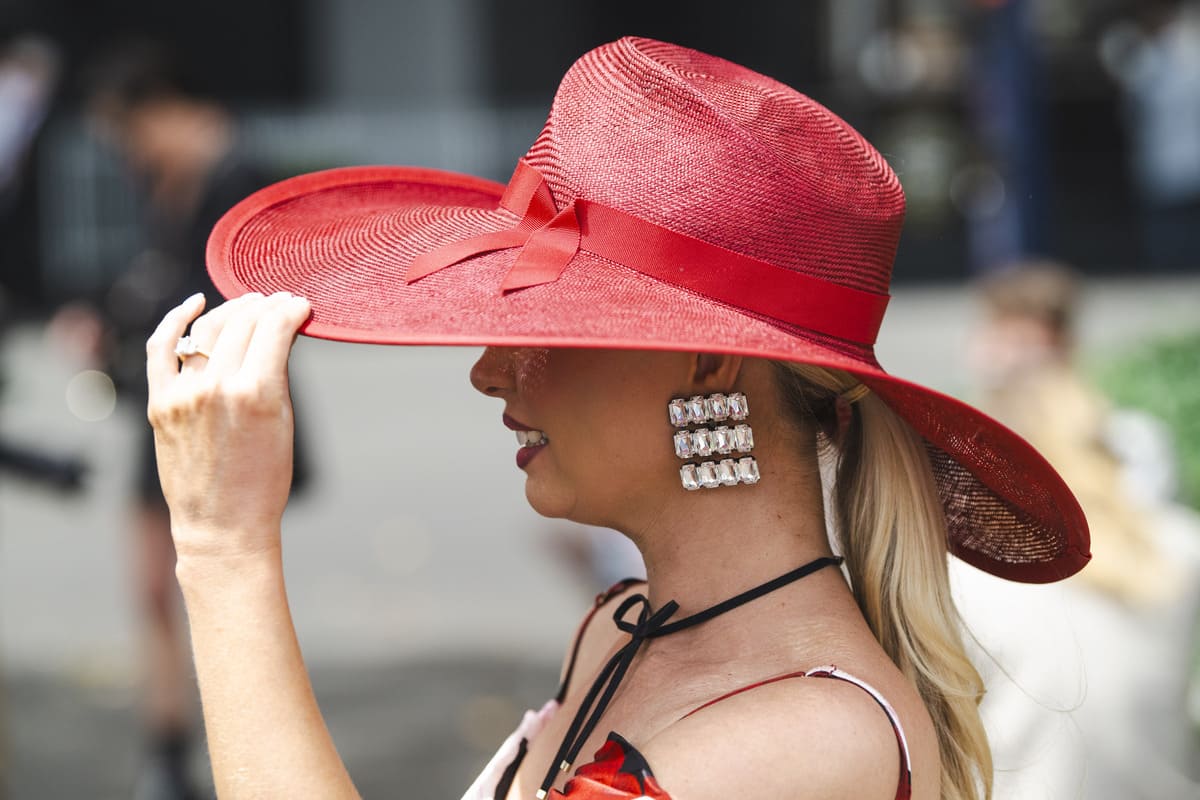 A female racegoer wearing a large red hat.