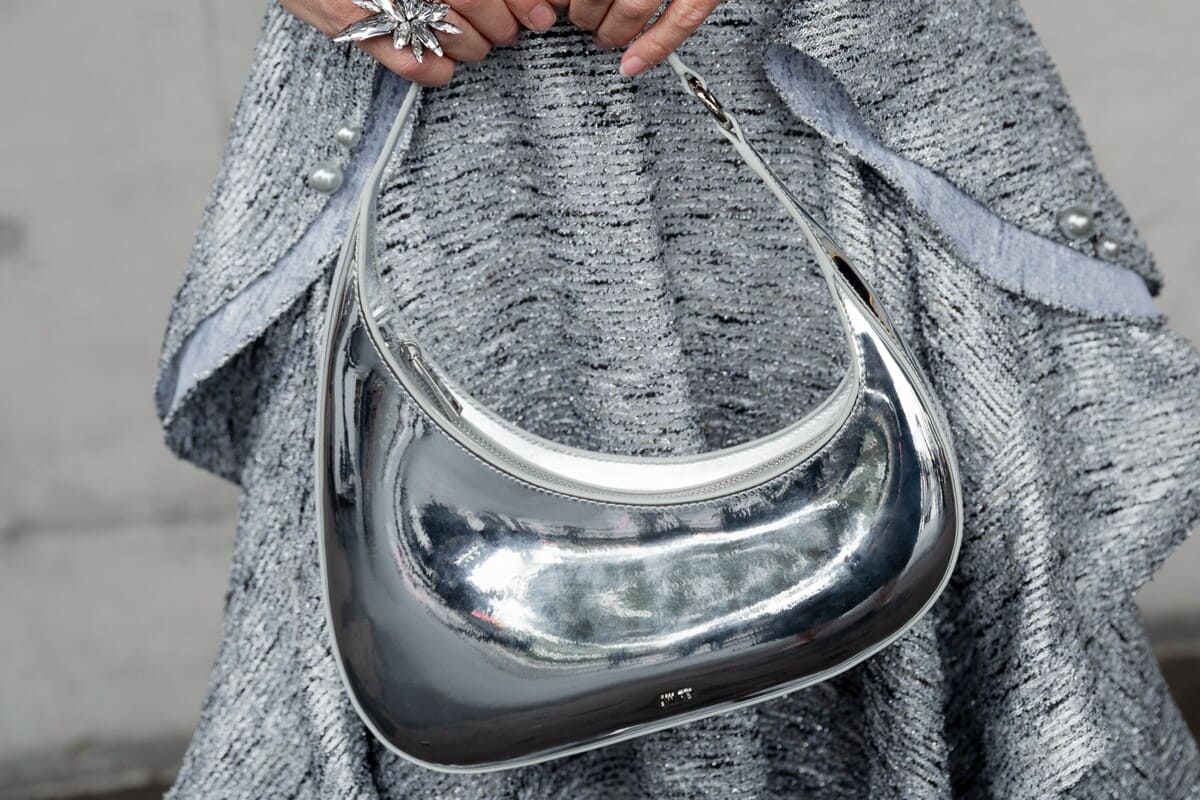 Close-up of a female racegoer holding a silver handbag.
