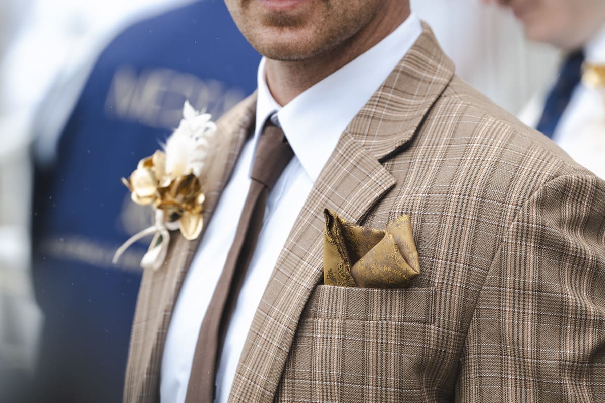 A male racegoer wearing a brown suit.