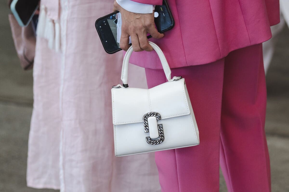 Close-up of a female racegoer holding a white handbag.
